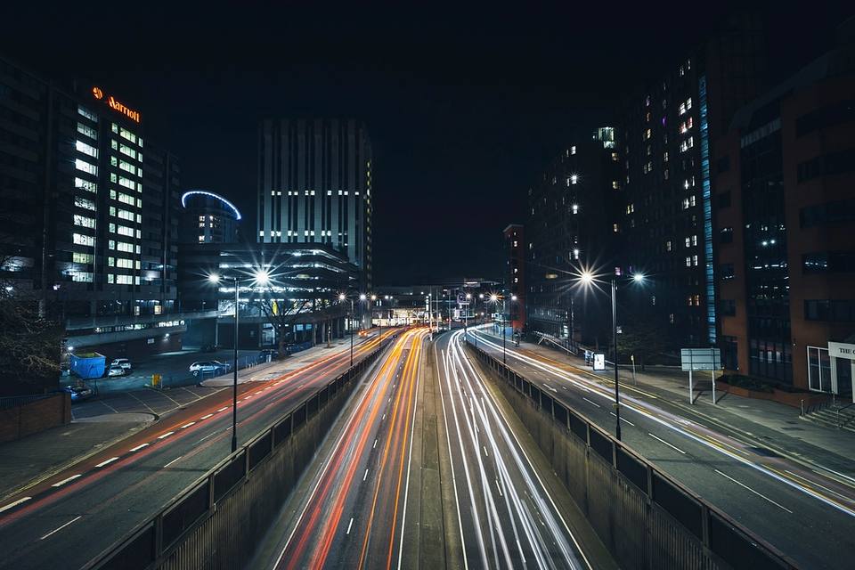Cruce urbano al anochecer con los faros de los autos dejando estelas de luz