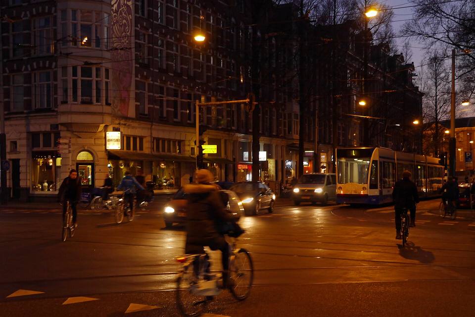 Avenida urbana durante la hora azul con las luces encendidas y el cielo todavía iluminado